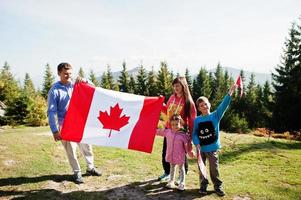 Happy Canada Day. Family with large Canadian flag celebration in mountains. photo