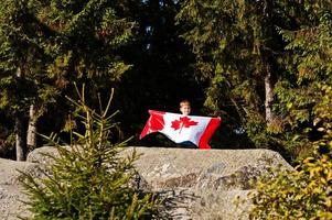 feliz dia DE CANADA. niño con gran celebración de la bandera canadiense en las montañas. foto