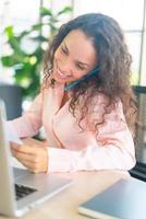 Latin woman working with phone on working space photo