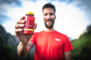 botella de cápsulas de energía en manos de deportistas foto