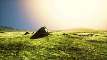 grote zandsteen en groene grasheuvelachtergrond video