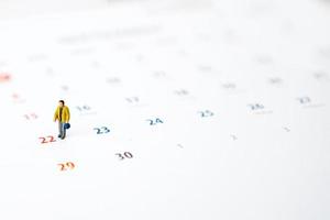 Miniature people of businessman standing on white calendar. Weekend time concept with copy space for your text or design. photo