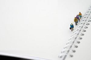 Miniature people in group walking on white blank Book. Business concept with copy space and white space for your text or design photo