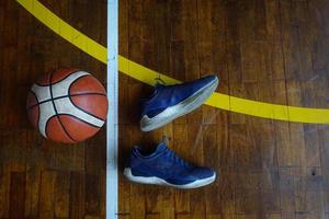 vista superior de los zapatos y la pelota de baloncesto en la cancha de baloncesto de madera foto