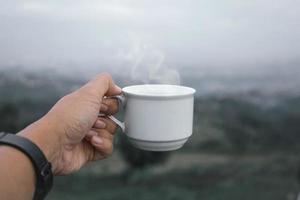 Hands holding tea cup on misty nature bokeh background. photo