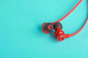 Red earphones on bright blue background photo