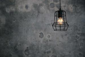 Hanging lightbulb industrial concept design. Cement background