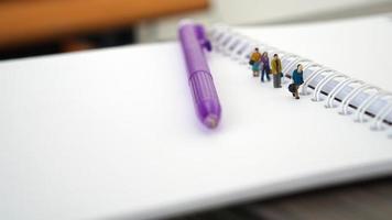 Miniature people in group walking on white blank Book. Business concept with copy space and white space for your text or design photo