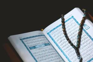 The holy Quran and rosary or tasbih on black background photo
