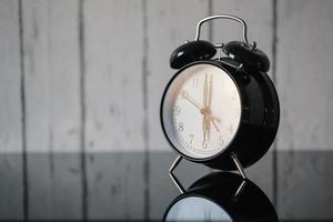 despertador en la mesa de cristal, despierta por la mañana, vintage. desenfoque de fondo de la pared foto