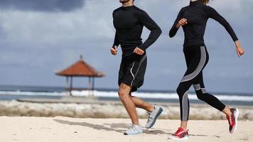 Couple jogging outside, runners training outdoors working out in nature.Health, exercise, weight loss concept. Couple doing beach jog.