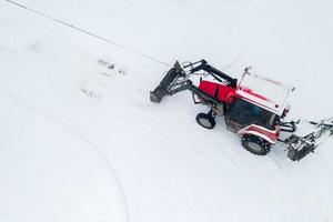 el tractor despeja el camino desde la vista superior de la nieve desde el trono. foto