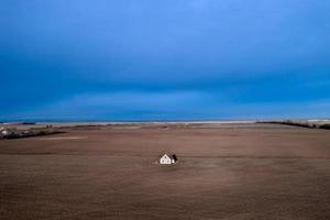 una casa abandonada en medio de un campo contra un cielo tormentoso. foto