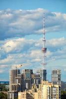 04.09.2021. kiev Ucrania. nuevos edificios urbanos de gran altura en construcción contra el fondo de una torre de televisión y un cielo azul de verano con nubes. foto