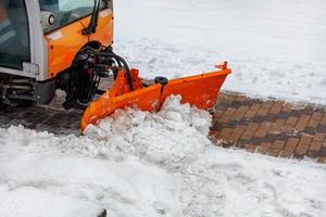 A municipal road sweeper cleans the sidewalk from snow. photo