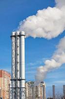 Puffs of smoke and steam rise into the sky from an urban thermal plant in a residential city block. photo