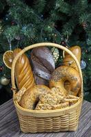 Bakery products. The bread lies in a wicker basket. Christmas fir tree with lights. photo