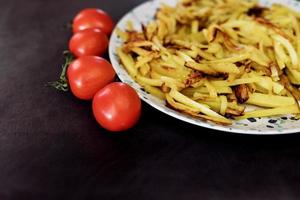 plato de papas fritas y tomates rojos foto