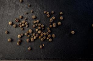 granos de pimienta negra en piedra foto