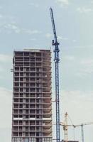 three building cranes at the background of a multi-storey building photo