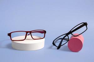 Classic glasses on a natural stone podium on a blue background. Optics. Closeup with copy space photo