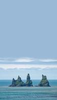 Cover page with view of basalt stacks, rocks or pillars called Reynisdrangar standing in ocean at black sand beach near Vik, South Iceland, summer, with blue sky solid background with copy space. photo