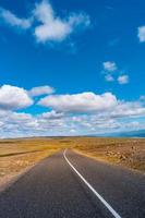 Highland landscape in Iceland, with paved asphalt road at summer sunny day and blue sky with clouds. photo