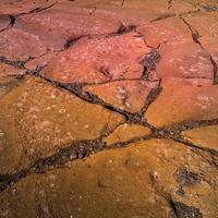 Colorful volcanic rocks with red and turquoise volcano soil with cracks and patterns as background. photo
