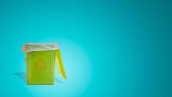 Banner with a green garbage trash bin with bag inside with its shadow and recycling symbol at turquoise gradient background with copy space. Concept of waste recycling. photo