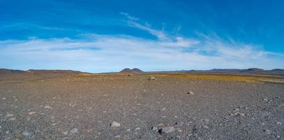 Panoramic view over Icelandic landscape of the deadliest volcanic desert in Highlands, with stones and rocks thrown by volcanic eruptions and hiking trek along the off road, Iceland, summer, blue sky. photo