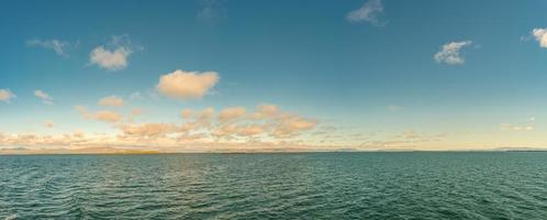 Panoramic view over remote islands in Atlantic ocean on the way to Iceland at summer time, during warm sunset with beautiful clouds. photo