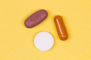 Multi-colored pills on a yellow background. Colorful medicines of different shapes on a bright backdrop. A group of antibiotics. Different pills on color background. Isolated. Close-up. Flat lay photo