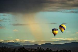 Two Hot Air Balloons In Flight with a Summer Morning shower nearby photo
