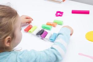 The girl at the table is playing with modeling dough. Childrens games for fine motor skills photo