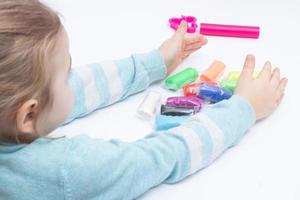 The girl at the table is playing with modeling dough. Childrens games for fine motor skills photo