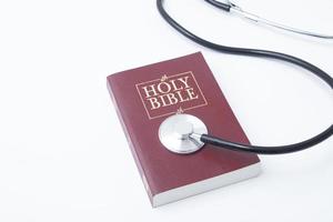 Holi bible with medical stethoscope on white background. Soul treatment concept photo