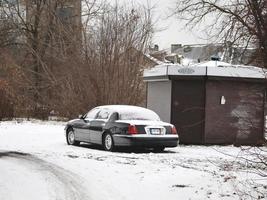 Black long car standing near closed kiosk covered in white snow photo