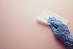 hand in blue rubber gloves cleaning table with cloth photo