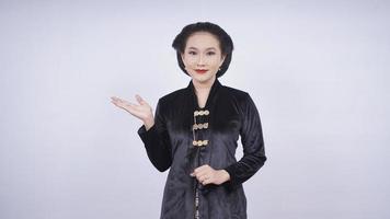 mujer asiática en kebaya sonriendo señalando el lado en blanco aislado en fondo blanco foto