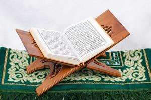the holy book al quran and prayer rug isolated on white background photo