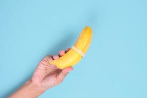 educational sex with banana in hand isolated on blue background photo