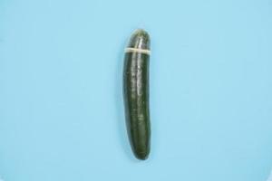 sex education with cucumber and contraception isolated on blue background photo