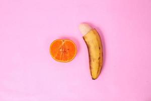 sex education with oranges and bananas isolated on pink background photo