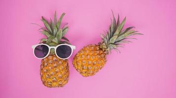 Pineapple with glasses isolated on a pink background photo