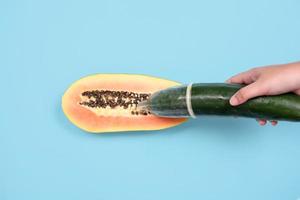 sex education with cucumber and contraception isolated on blue background photo