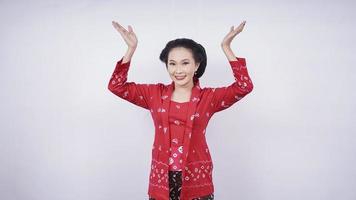 hermosa asiática en kebaya apuntando sin expresión hacia arriba aislada en fondo blanco foto
