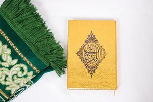 the holy book al quran and prayer rug isolated on white background photo