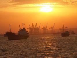 buque de carga y grúas en el puerto de tanjung perak surabaya con fondo de cielo al atardecer. foto