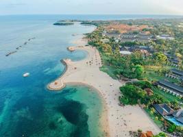 Aerial drone view of Holiday In Sanur Beach, Bali, Indonesia with ocean, boats, beach, villas, and people. photo