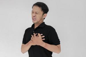 ataque al corazón o corazón roto de un joven asiático con una emoción herida que usa camisa negra foto